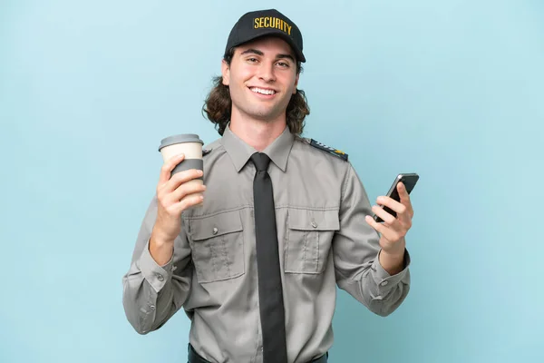 Jonge Veiligheidsman Geïsoleerd Blauwe Achtergrond Met Koffie Mee Nemen Een — Stockfoto