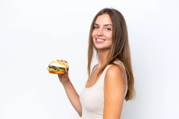 Młoda Ładna Kobieta Trzyma Hamburgera Odizolowany Białym Tle Uśmiechając Się — Zdjęcie stockowe