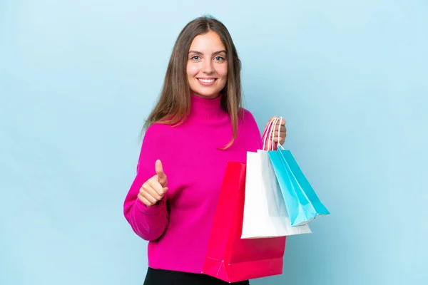 Jonge Mooie Vrouw Geïsoleerd Blauwe Achtergrond Holding Boodschappentassen Met Duim — Stockfoto