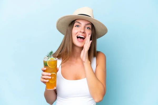stock image Young beautiful woman holding a cocktail isolated on blue background shouting with mouth wide open