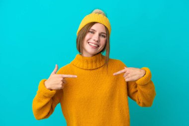 Kışlık ceket giyen genç İngiliz kadın mavi arka planda soyutlanmış gururlu ve kendini beğenmiş.