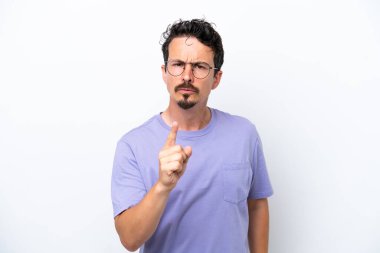 Bıyıklı genç adam beyaz arka planda izole edilmiş hayal kırıklığına uğramış ve ön tarafı işaret ediyor.