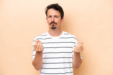 Beyazlı genç adam bej arka planda izole edilmiş para hareketi yapıyor ama mahvolmuş.