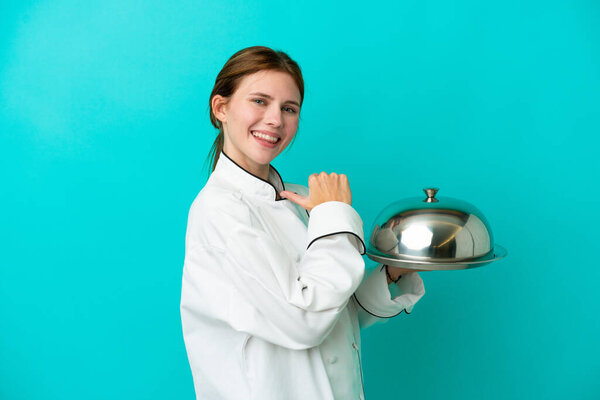 Young chef woman with tray isolated on blue background proud and self-satisfied