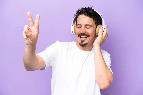 Young Caucasian Man Isolated Purple Background Listening Music Singing — Zdjęcie stockowe