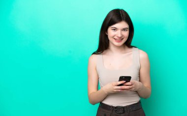Genç Rus kadın yeşil arka planda izole edilmiş cep telefonuyla mesaj gönderiyor.