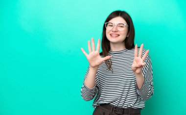 Yeşil arka planda izole edilmiş genç Rus kadın parmaklarıyla sekizi sayıyor