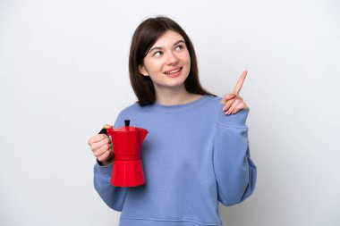 Beyaz arka planda kahve demliği tutan genç Rus kadın harika bir fikre işaret ediyor.