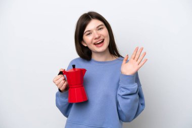 Beyaz arka planda kahve demliği tutan genç Rus kadın mutlu bir ifadeyle selamlıyor.