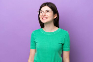 Genç, güzel bir Rus kadın, mor arka planda izole edilmiş, mutlu bir ifadeyle gözlüklü.