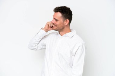 Beyaz arka planda izole edilmiş beyaz tenli yakışıklı bir adam cep telefonuyla sohbet ediyor.