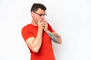 Beyaz arka planda izole edilmiş beyaz tenli yakışıklı bir adam ağzını kapatıyor ve yan tarafa bakıyor.