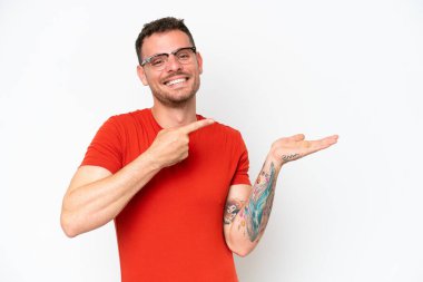 Beyaz arka planda izole edilmiş beyaz tenli yakışıklı bir adam, bir ilan vermek için avucunda hayali bir fotokopi makinesi tutuyor.