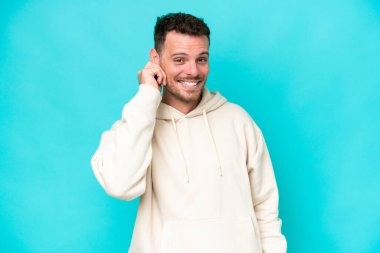 Genç beyaz yakışıklı adam mavi arka planda izole edilmiş gülüyor.