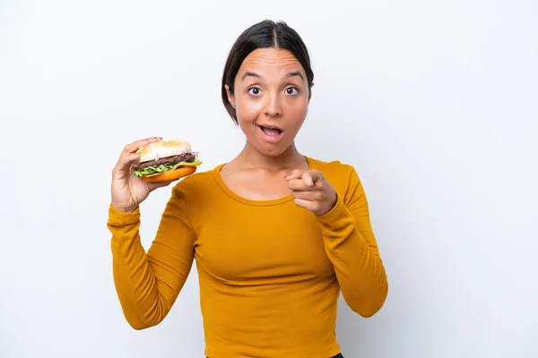Młoda Latynoska Kobieta Trzyma Hamburgera Odizolowanego Białym Tle Zaskoczona Skierowana — Zdjęcie stockowe