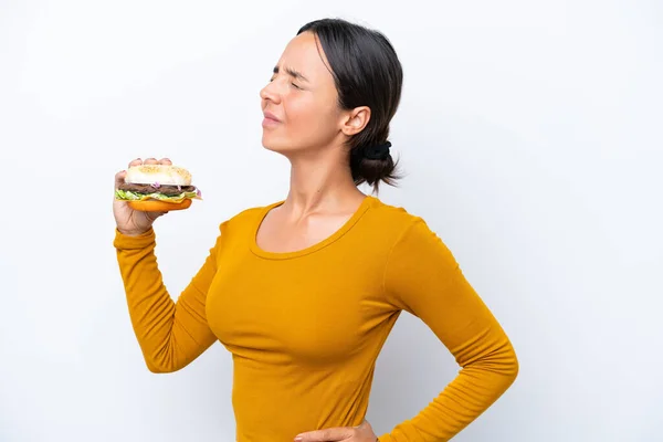 Młoda Latynoska Kobieta Trzyma Hamburgera Białym Tle Cierpiącego Bóle Pleców — Zdjęcie stockowe