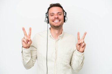 Beyaz arka planda izole edilmiş bir kulaklıkla çalışan beyaz pazarlamacı, zafer işaretini iki eliyle de gösteriyor.