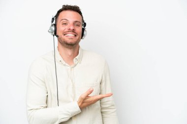 Beyaz arka planda izole edilmiş bir kulaklıkla çalışan beyaz pazarlamacı bir fikir sunarken aynı zamanda gülümsüyor.