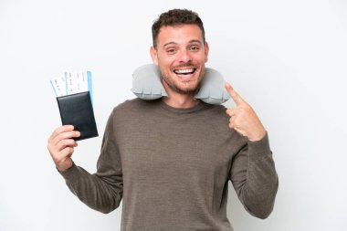 Beyaz arka planda izole edilmiş pasaport taşıyan genç beyaz bir adam baş parmak hareketi yapıyor.