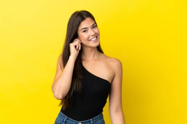 Genç Brezilyalı kadın sarı arka planda izole edilmiş gülüyor.