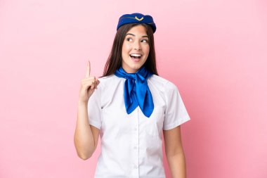 Uçak hostesi Brezilyalı kadın pembe arka planda izole edilmiş. Çözümün farkına varmak için parmağını kaldırıyor.