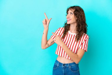 Mavi arka planda izole edilmiş kıvırcık saçlı genç kadın işaret parmağıyla işaret etmek harika bir fikir.