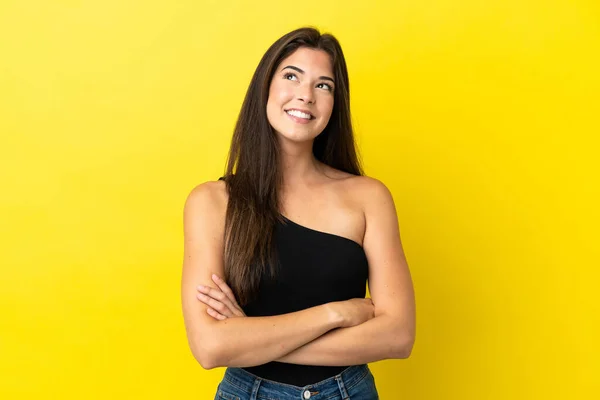 Jovem Brasileira Isolada Fundo Amarelo Olhando Para Cima Enquanto Sorri — Fotografia de Stock