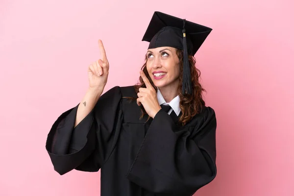 Junge Universitätsabsolventin Isoliert Auf Rosa Hintergrund Zeigt Mit Dem Zeigefinger — Stockfoto