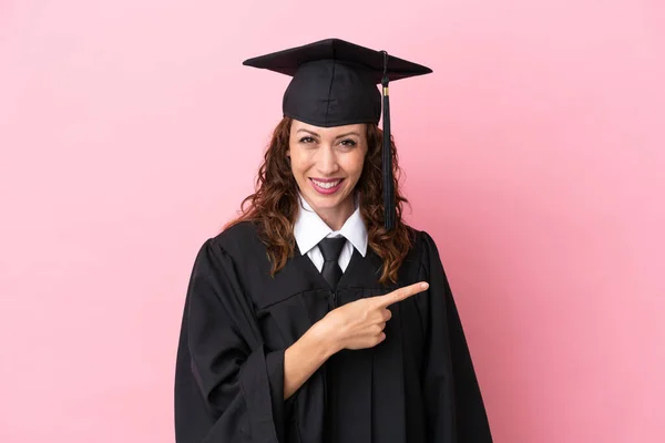 Νεαρή Απόφοιτος Πανεπιστημίου Γυναίκα Απομονωμένη Ροζ Φόντο Δείχνοντας Δάχτυλο Στο — Φωτογραφία Αρχείου