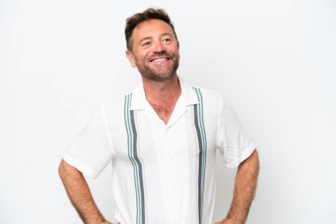 Beyaz arka planda izole edilmiş orta yaşlı beyaz bir adam kolları kalçasında ve gülümsüyor.