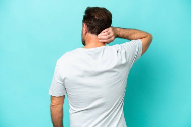 Orta yaşlı beyaz bir adam mavi arka planda izole edilmiş ve düşünüyor.