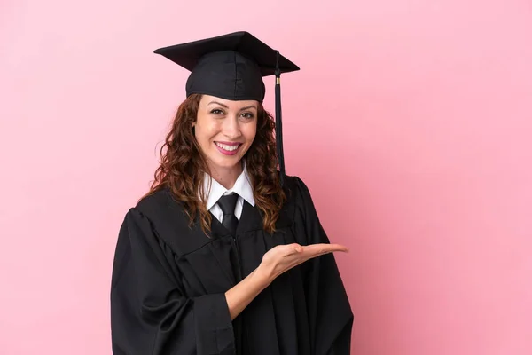 Молодая Выпускница Университета Изолирована Розовом Фоне Представляя Идею Глядя Улыбаясь — стоковое фото