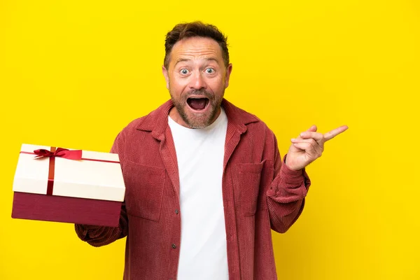Middle Age Caucasian Man Holding Gift Isolated Yellow Background Surprised — Stock Photo, Image