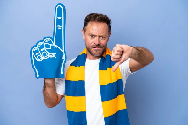 Middle age caucasian sports fan man isolated on blue background showing thumb down with negative expression