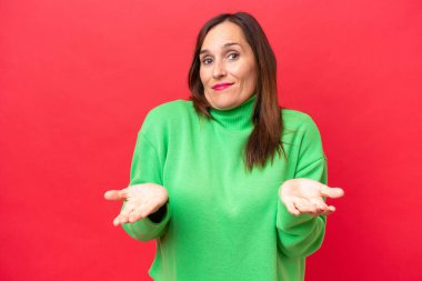 Orta yaşlı beyaz kadın, kırmızı arka planda izole edilmiş, kuşkuları var.