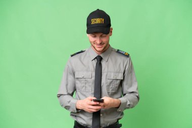 İzole edilmiş arka planda genç bir beyaz adam cep telefonuyla mesaj gönderiyor.