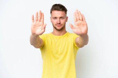 Beyaz arka planda izole edilmiş genç sarışın adam dur hareketi yapıyor ve hayal kırıklığına uğruyor.