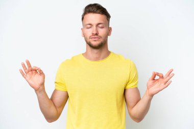 Zen pozisyonunda beyaz arka planda izole edilmiş genç sarışın beyaz adam.