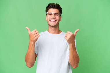 Kafkasyalı yakışıklı bir adam soyutlanmış bir geçmişi var. Başparmakları havada ve gülümsüyor.