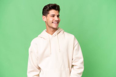 Kafkasyalı yakışıklı, soyutlanmış arka planda, yana bakıyor ve gülümsüyor.