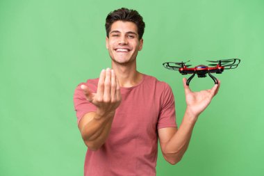 Kafkasyalı genç bir adam arka planda İHA tutuyor ve bizimle gelmesi için davet ediyor. Gelmene sevindim.