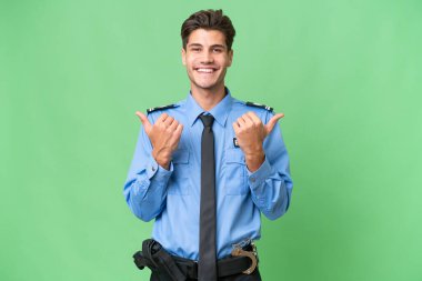 Soyutlanmış bir geçmişi olan genç bir polis memuru. Başparmakları havada ve gülümsüyor.