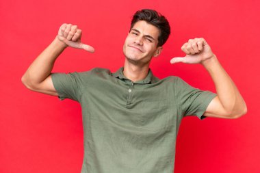 Kızıl arka planda yalnız, gururlu ve kendini beğenmiş, beyaz, yakışıklı genç bir adam.