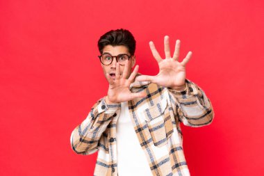 Genç, beyaz, yakışıklı, kırmızı arka planda izole edilmiş gergin eller öne doğru uzanıyor.