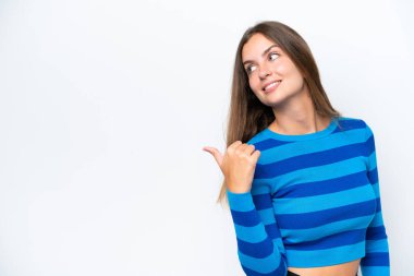 Beyaz arka planda izole edilmiş genç beyaz kadın bir ürünü sunmak için kenarı işaret ediyor.