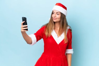 Anne Noel gibi giyinmiş beyaz bir kadın mavi arka planda izole edilmiş bir şekilde selfie çekiyor.