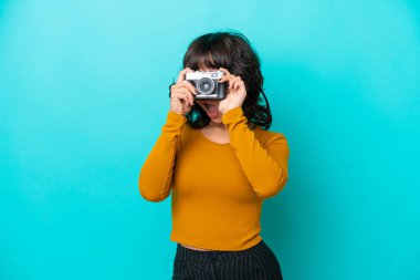 Genç fotoğrafçı latin kadın mavi arka planda izole edilmiş