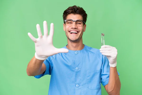 Jovem Dentista Homem Segurando Ferramentas Sobre Fundo Isolado Contando Cinco — Fotografia de Stock