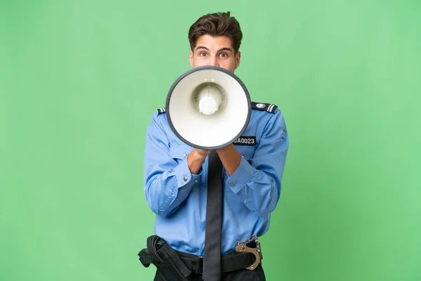 Young police man over isolated background shouting through a megaphone