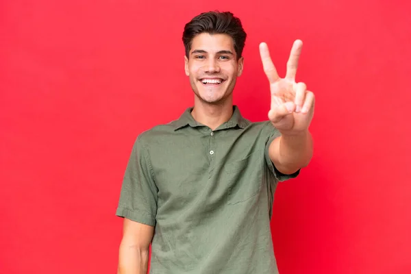 Kızıl Arka Planda Izole Edilmiş Genç Beyaz Adam Gülümsüyor Zafer — Stok fotoğraf